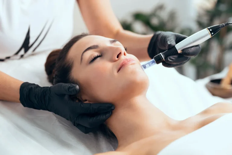 A woman receives a facial treatment with a microneedling device. Black-gloved hands hold the tool, conveying a sense of relaxation and professional care.